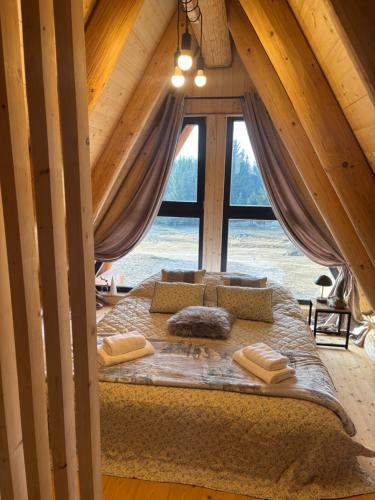 a bed in a room with a large window at A mon Chalet in Vărşag