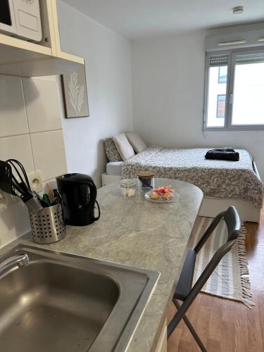 - une cuisine avec évier et un lit dans une chambre dans l'établissement Charmant studio à 20min de Paris, à Créteil