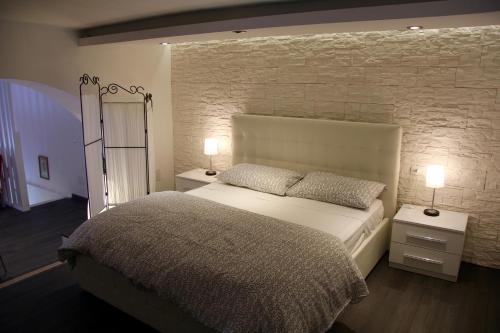 a bedroom with a large bed and a brick wall at Katana Apartments in Catania