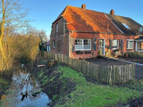 a brick house with a fence in front of it at Huus an`t Dörpsdiek in Krummhörn