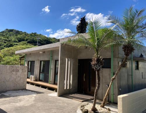a building with two palm trees in front of it at Pool and Sauna villa Kanasa in Motobu