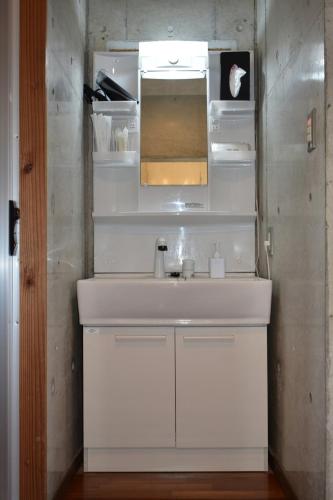 a bathroom with a white sink and a mirror at Pool and Sauna villa Kanasa in Motobu