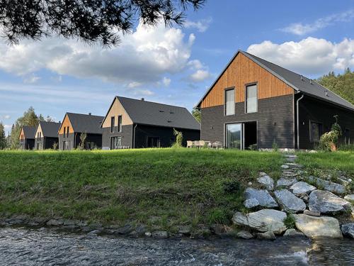 a group of houses on a field next to a river at Wellness Chalupy LETOKRUHY in Jeseník