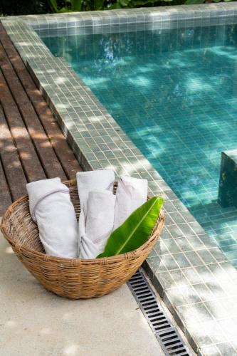 a basket of towels sitting next to a swimming pool at SITIO VILLA DA MATA in São Miguel dos Milagres