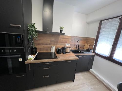 - une cuisine avec des placards noirs et un évier dans l'établissement Havre de Livia, cosy T2 meuble proche plage, à Six-Fours-les-Plages