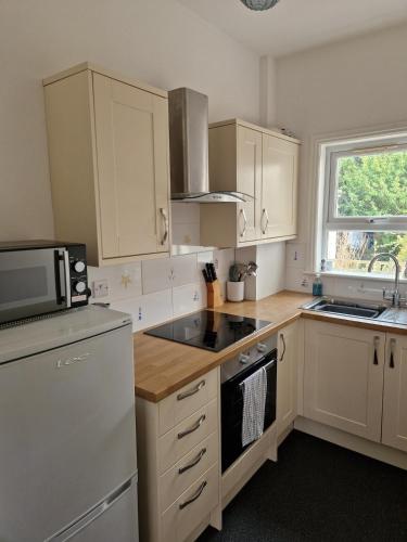 a kitchen with white cabinets and a stove top oven at Unique Exmouth Family Holiday Home Close to Beach & Town in Exmouth