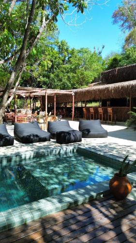 a swimming pool with pillows and a table and chairs at SITIO VILLA DA MATA in São Miguel dos Milagres