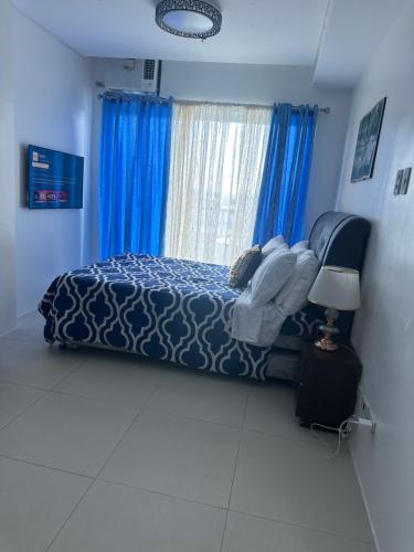 a bedroom with a bed with blue sheets and blue curtains at Primavera Cozy studio Condominium, Cagayan de Oro City, Philippines in Cagayan de Oro