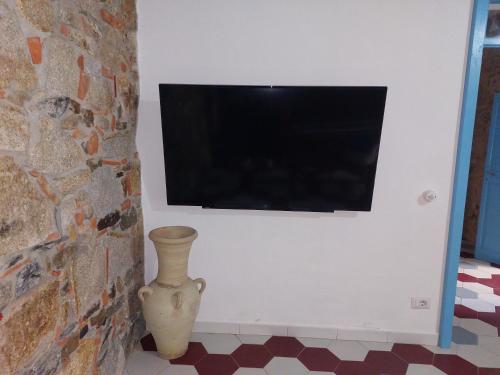 a television on a wall with a vase in a room at Su Furriadroxiu in San Vito