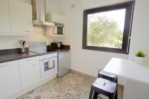 une cuisine avec des armoires blanches et une fenêtre dans l'établissement Seignosse - Forêt - Lac - Ocean - Couple - Surf, à Seignosse