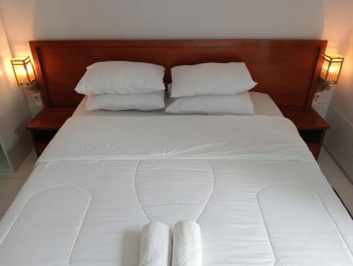 a white bed with two white pillows and a wooden headboard at BTN Mahkota Pemenang 13 Tamarin 3A in Pawenang