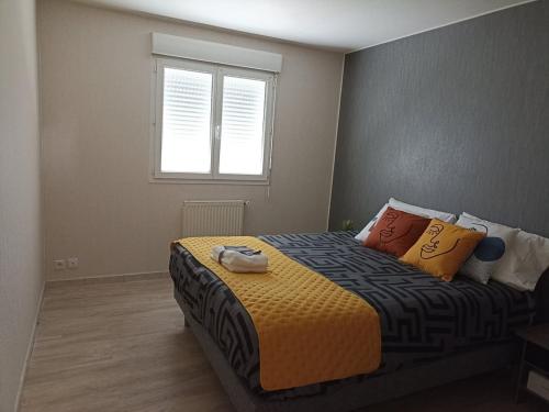 a bedroom with a bed with colorful pillows and a window at Cozy T3 appartement 70m2- Plescop in Plescop