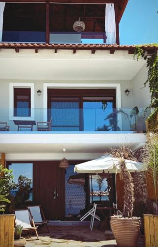 a house with a patio with an umbrella and chairs at Casa Del Mar Thassos in Skala Sotiros