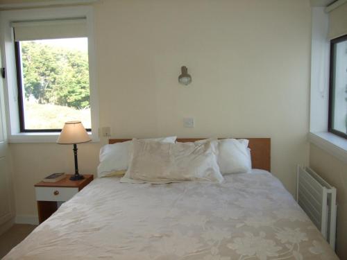 a bed with white pillows and a window in a bedroom at Ardeevan Schull in Schull