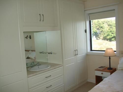 a white bathroom with a sink and a window at Ardeevan Schull in Schull