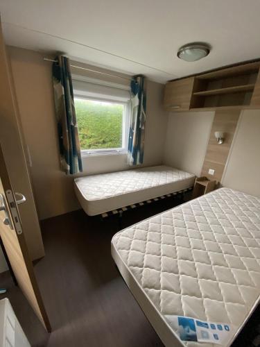 une petite chambre avec deux lits et une fenêtre dans l'établissement MobilHome Camping Deauville, à Saint-Arnoult