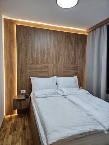 a large white bed with a wooden head board at Apartmani Corner in Jahorina