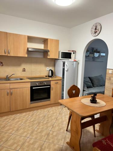 a kitchen with wooden cabinets and a table and a dining room at Penzion Mánes in Krabčice
