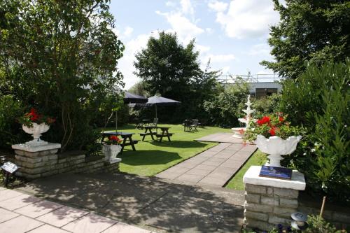 a garden with two white vases and a patio with tables at London Croydon Aerodrome Hotel, BW Signature Collection in Croydon