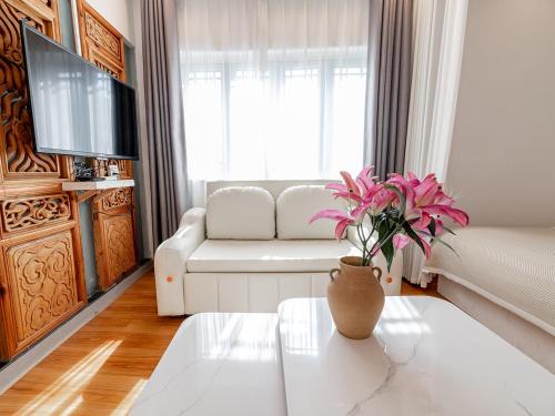 a living room with a couch and a vase with flowers on a table at Lijiang Old Town Meiliju View Inn in Lijiang