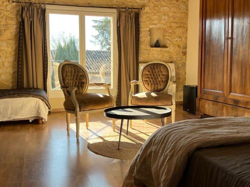 a bedroom with two chairs and a bed and a window at La Maison Des Autres, piscine chauffée, chambres d'hôtes proches Uzès, Nîmes, Pont du Gard in Saint-Géniès-de-Malgoirès