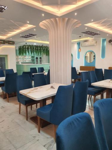 a restaurant with blue chairs and tables and a column at HOTEL DEO VOLENTE in Sivasagar