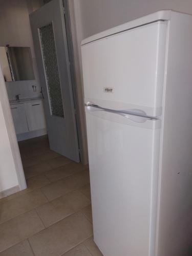 a white refrigerator in a room with a kitchen at Su Furriadroxiu in San Vito