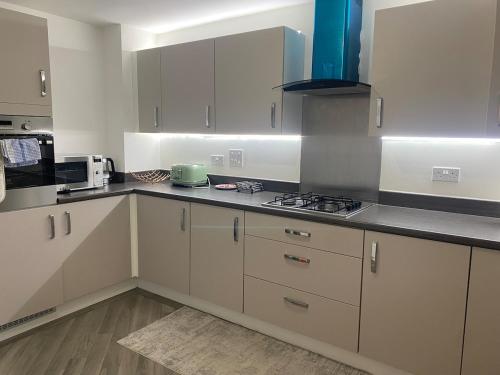 a kitchen with white cabinets and a stove top oven at 4 Bed Station Garden House in Basingstoke