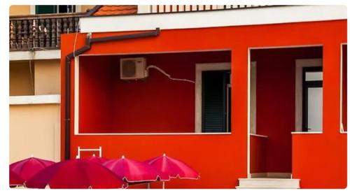 a row of red umbrellas in front of a building at Дарина in Igalo