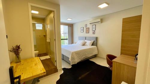 Un dormitorio con una cama, una mesa y un espejo. en Nô Centro Suítes 2 - Apto moderno com cozinha compartilhada, en Florianópolis