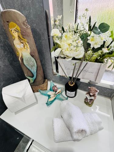 a bathroom counter with a vase of flowers and towels at Park Road Holiday Home - Spacious 3 bedroom house with garden near Edinburgh in Rosyth