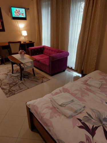 a bedroom with a bed and a couch and a table at Penzion Vegas in Partizánske