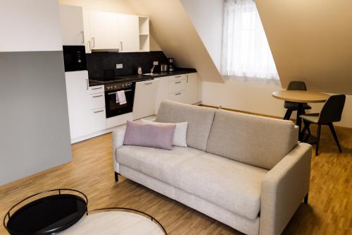 a living room with a couch and a kitchen at Altes Bräuhaus, Ferienwohnungen und Apartments in Gaildorf in Gaildorf