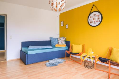 a living room with a blue couch and yellow wall at Angela Apartments in Würzburg