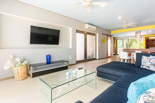 a living room with a blue couch and a tv at Experience tranquility and comfort accommodation, near main attractions in Riviera Maya in Lafitte