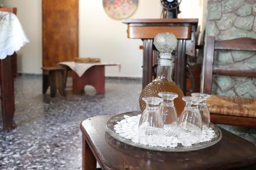 a table with a bottle and three glasses on it at Mary's house in Makrikhórion