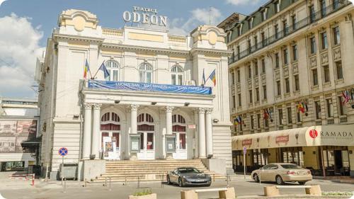 a white building with cars parked in front of it at Sunrise Apartments City Center in Bucharest