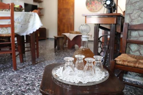 a table with a bottle and four glasses on it at Mary's house in Makrikhórion