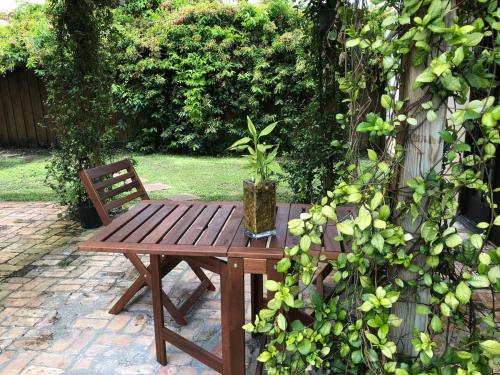 a wooden table and a bench with a potted plant on it at Kusikuy Private Guesthouse in Miami