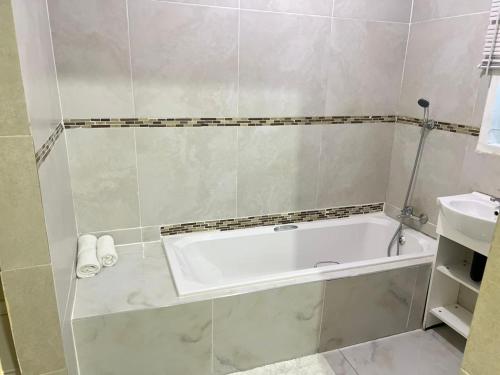 a bathroom with a bath tub and a sink at Oteng Lifestyle BnB in Rustenburg