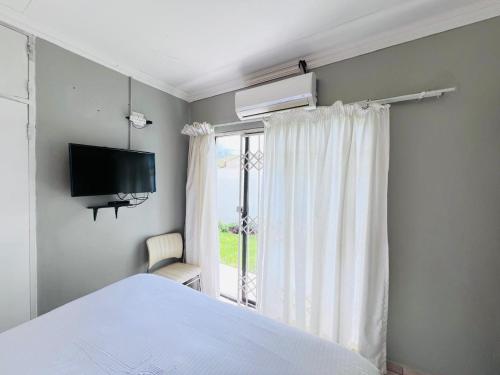 a bedroom with a bed and a tv and a window at Oteng Lifestyle BnB in Rustenburg