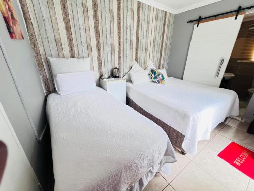 a hotel room with two beds with white sheets at Oteng Lifestyle BnB in Rustenburg