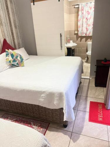 a bedroom with two beds and a bathroom at Oteng Lifestyle BnB in Rustenburg