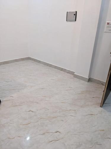 a room with a white wall and a tile floor at OM Rama Home Stay in Daryābād