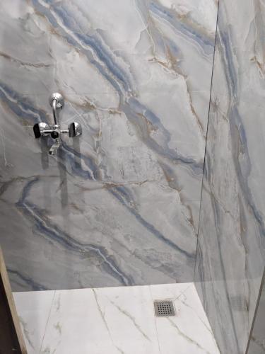 a bathroom with a marble shower with a sink at OM Rama Home Stay in Daryābād