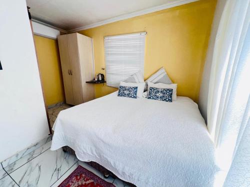 a bedroom with a white bed with blue pillows at Oteng Lifestyle BnB in Rustenburg