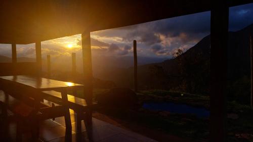 a view of the sunset from a house with a table at Cabana do Camelo in São Bento do Sapucaí