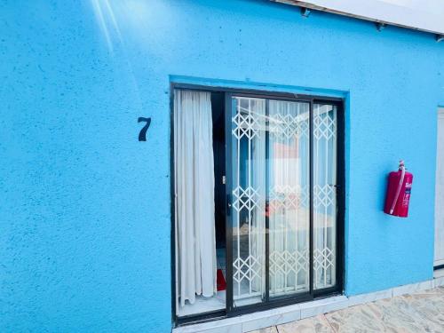 a blue building with a window with a fire extinguisher at Oteng Lifestyle BnB in Rustenburg