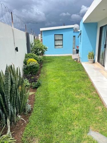a yard in front of a blue house at Oteng Lifestyle BnB in Rustenburg