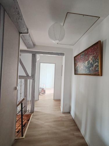 an empty hallway with a painting on the wall and a staircase at Gîte de la cour Ronty in Thin-le-Moutier